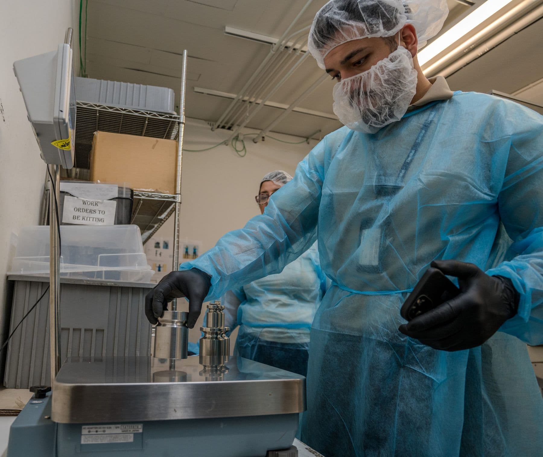 Technician placing stainless steel test weights on a bench scale